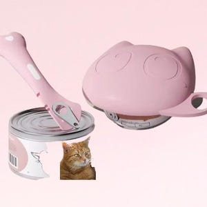 K&ouml;nnte beinhalten: Rosaer Katzen-f&ouml;rmiger Dosen&ouml;ffner mit Griff und einem separaten rosa Dosen&ouml;ffner-Werkzeug. Das Dosen&ouml;ffner-Werkzeug liegt auf einer Dose Katzenfutter mit einem Katzenbild auf dem Etikett.