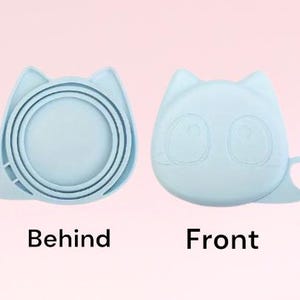 K&ouml;nnte beinhalten: Ein hellblauer, katzenf&ouml;rmiger Lebensmittelbeh&auml;lter aus Silikon mit Deckel. Der Beh&auml;lter hat eine runde, schalenartige Form und ist zum Aufbewahren von Lebensmitteln gedacht. Der Deckel hat ein Katzen Gesicht mit Augen und einer Nase. Der Beh&auml;lter wird von vorne und hinten gezeigt.