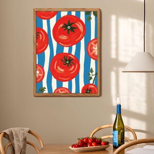 May include: A framed print with a red tomato pattern on a blue and white striped background. The tomatoes are painted in a stylized manner with a red, orange, and yellow color scheme.