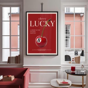 K&ouml;nnte beinhalten: Ein rotes und wei&szlig;es Poster mit dem Text "cherry lucky" und einer Kirsche auf einer roten Billardkugel mit der Nummer 8. Der Text unter der Kirsche lautet "A cherry on top of good fortune!"