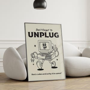 Op de afbeelding: Een ingelijste poster met een retro cartoon computerpersonage, die een stekker vasthoudt en loopt. De poster heeft de tekst "Don't Forget To UNPLUG" en "There's a whole world waiting to be explored!" in zwart op een cr&egrave;mekleurige achtergrond.