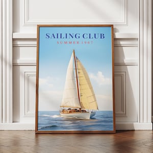 Puede incluir: Un cuadro enmarcado con un velero navegando sobre el agua bajo un cielo azul. El cuadro tiene las palabras "SAILING CLUB SUMMER 1967" en texto rojo y azul. El marco es de color marrón oscuro.
