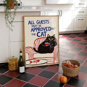 Puede incluir: Un póster enmarcado con el texto "ALL GUESTS MUST BE APPROVED BY THE CAT" y un gato de dibujos animados sosteniendo una taza. El gato está sentado en un sillón a rayas rojas y blancas. Una botella de vino y un tarro de pasta están en primer plano.