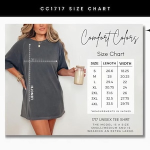 May include: A size chart for a Comfort Colors 1717 unisex tee shirt. The chart shows measurements in inches for sizes S through 4XL. The model is wearing an extra large. The shirt is a dark gray color.
