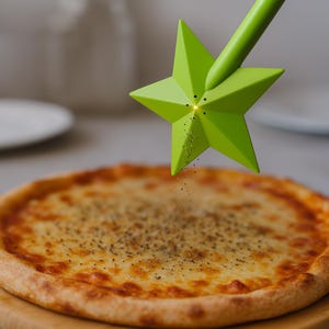 Op de afbeelding: Een groene, stervormige pepermolen strooit kruiden op een pizza. De pizza heeft een goudbruine korst en is belegd met gesmolten kaas. De pepermolen wordt boven de pizza gehouden, waarbij pepervlokken op de kaas vallen.