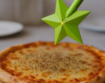 May include: A green star-shaped pepper shaker sprinkles seasoning onto a pizza. The pizza has a golden-brown crust and is topped with melted cheese. The pepper shaker is held over the pizza, with pepper flakes falling onto the cheese.