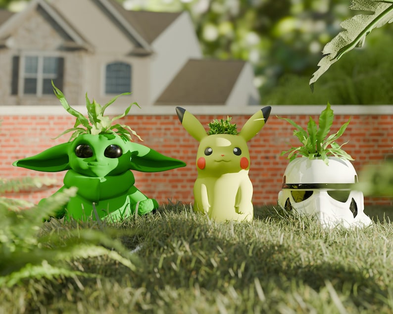 May include: Three character-themed planters sit in grass. A green Baby Yoda planter, a yellow Pikachu planter, and a white Stormtrooper planter, each with a small plant sprouting from the top. The planters are in front of a brick wall and a house.