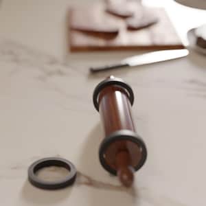 May include: A wooden rolling pin with black accents and a detached black ring sits on a light-colored surface. A wooden cutting board and knife are in the background, suggesting a baking or cooking theme.