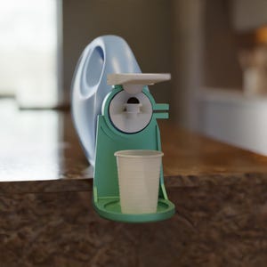 Può includere: Un contenitore di plastica blu chiaro e una macchina da caffè turchese e bianca con un bicchiere usa e getta bianco. La macchina ha un design circolare con un beccuccio e un vassoio per la tazza. Lo sfondo è sfocato.