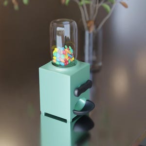 May include: A mint green gumball machine with a clear glass top filled with colorful candies. The machine has a black handle and a dispensing area. A decorative item for a desk or counter.