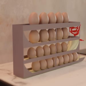 Könnte beinhalten: Ein dreistufiger Eierhalter aus grauem Material, gefüllt mit braunen Eiern. Der Halter steht auf einer weißen Arbeitsplatte. Der Hintergrund ist eine hellfarbige Wand und ein Kochfeld.