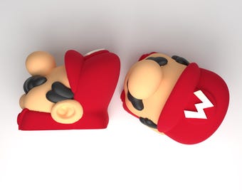 May include: Two 3D-rendered figures of Mario's head, a popular video game character. The figures are in a side profile, showcasing his tan skin, black mustache, and red hat with a white "M" on the front. The background is plain white.