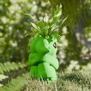 May include: A vibrant green, stylized planter shaped like a character, holding a plant with green and white leaves. The planter has a smooth, rounded design and a single eye. The image is set outdoors in a grassy area with a blurred background of green foliage.