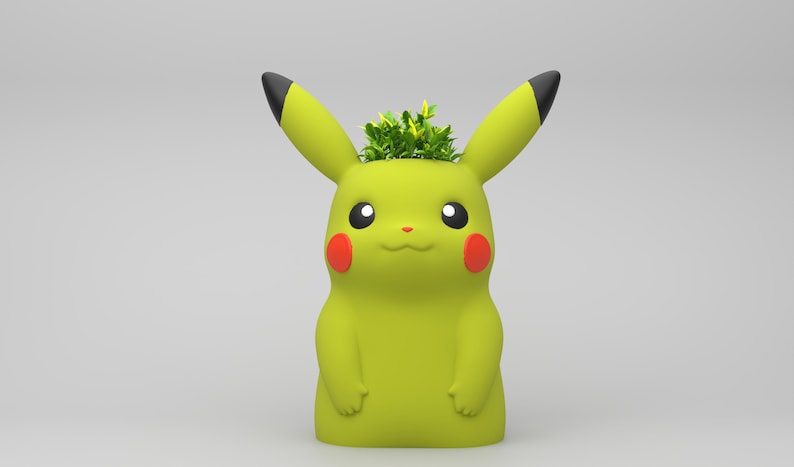May include: A yellow Pikachu planter with black-tipped ears and red cheeks. The planter is filled with green plants. The design is based on the popular Pok&eacute;mon character. The planter is a decorative item.