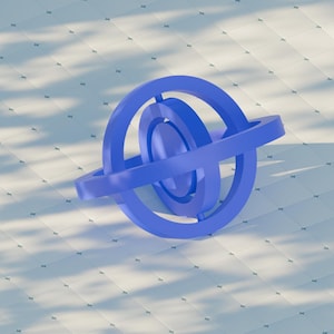 May include: A blue geometric sculpture featuring three concentric rings and a surrounding band. The object is a solid, three-dimensional form, set against a white tiled surface with shadows.