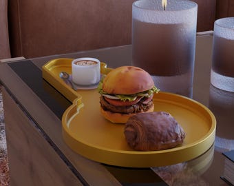 May include: A yellow guitar-shaped serving tray holds a small cup of coffee with a spoon, a hamburger, and a chocolate croissant. A lit candle and a glass are in the background. The tray sits on a glass table.