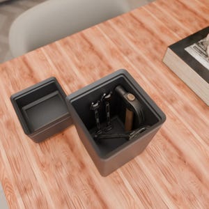 May include: A dark gray toolbox with its lid open, revealing various tools. Inside are two wrenches, a hammer, and a pair of pliers. The toolbox sits on a wooden surface.