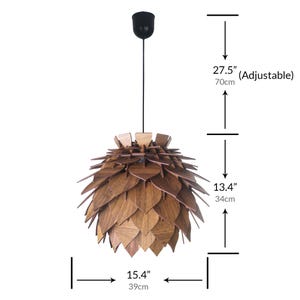 May include: A wooden pendant light fixture with a leaf-like design. The light is 15.4 inches (39cm) wide and 13.4 inches (34cm) tall, with an adjustable height up to 27.5 inches (70cm). The fixture has a black ceiling mount.