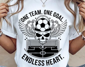 May include: White t-shirt with a black graphic design featuring a skull with wings, a soccer ball, and a soccer field. The text "ONE TEAM. ONE GOAL. ENDLESS HEART." is printed on the shirt.