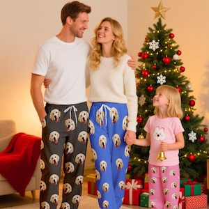 Könnte beinhalten: Eine Familie posiert vor einem Weihnachtsbaum, jede Person trägt eine Schlafhose mit einem sich wiederholenden Muster von Golden Retriever-Gesichtern. Die Hosen sind in Schwarz, Blau und Rosa gehalten. Das Mädchen hält eine Glocke.