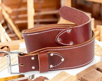 以下が含まれることがあります： 白いステッチとシルバーのバックルが付いた茶色の革製作業用ベルト。 ベルトは厚くて丈夫で、ヘビーデューティーな使用のために設計されています。 ベルトは、背景に木工道具がある白い表面に巻かれて表示されています。