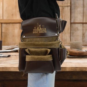 May include: A brown leather tool belt with multiple pockets and a brown suede flap. The belt has a gold logo that reads "Bolt Belts" with a graphic of tools above the text.