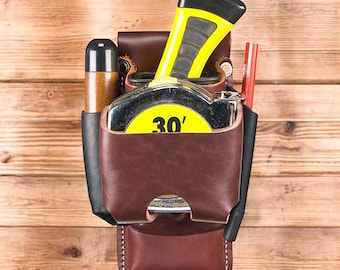 Estuche de cuero para cinta métrica con ranuras para herramientas y clip.