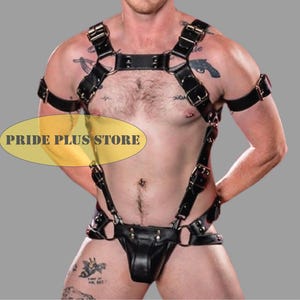 May include: Black leather body harness with multiple straps, buckles, and a jockstrap-style bottom. The harness features adjustable straps and metal hardware. The image includes the text "PRIDE PLUS STORE".