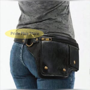 May include: Black leather fanny pack with multiple pockets and a gold-colored zipper. The pack is worn around the waist and has a belt with a gold-colored buckle. The text "Pride Plus Store" is visible.