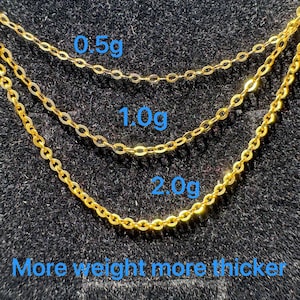 May include: Three gold-colored metal chains of varying thicknesses arranged in a cascading pattern. The chains are labeled with the weights 0.5g, 1.0g, and 2.0g, with the text "More weight more thicker" displayed at the bottom of the image.