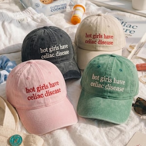 Può includere: Quattro cappellini da baseball in rosa, grigio antracite, beige e verde salvia. Ogni cappellino presenta il testo ricamato "hot girls have celiac disease" in un colore a contrasto. I cappellini hanno una corona strutturata, una visiera curva e occhielli.