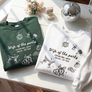May include: Two sweatshirts, one dark green and one white, with the text "Wife of the party" and "FUTURE MRS. SMITH DALLAS - EST 2026". The design includes a disco ball, champagne, flowers, and other wedding-themed graphics.
