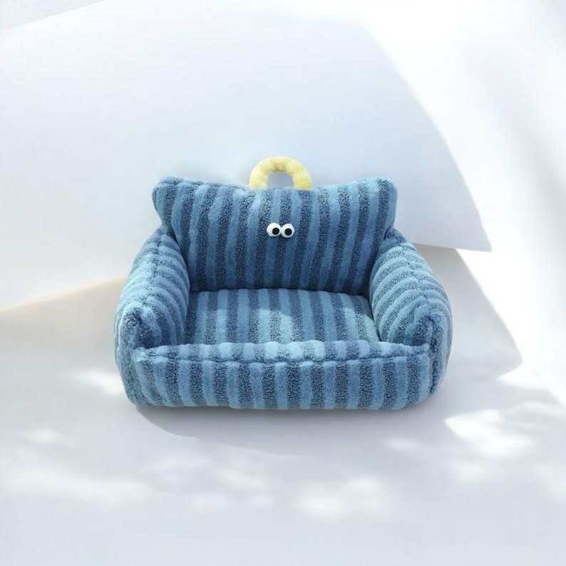 Peut inclure: Un lit pour chien en peluche bleu et blanc ray&eacute; en forme de canap&eacute; avec une poign&eacute;e en boucle jaune et deux yeux blancs.