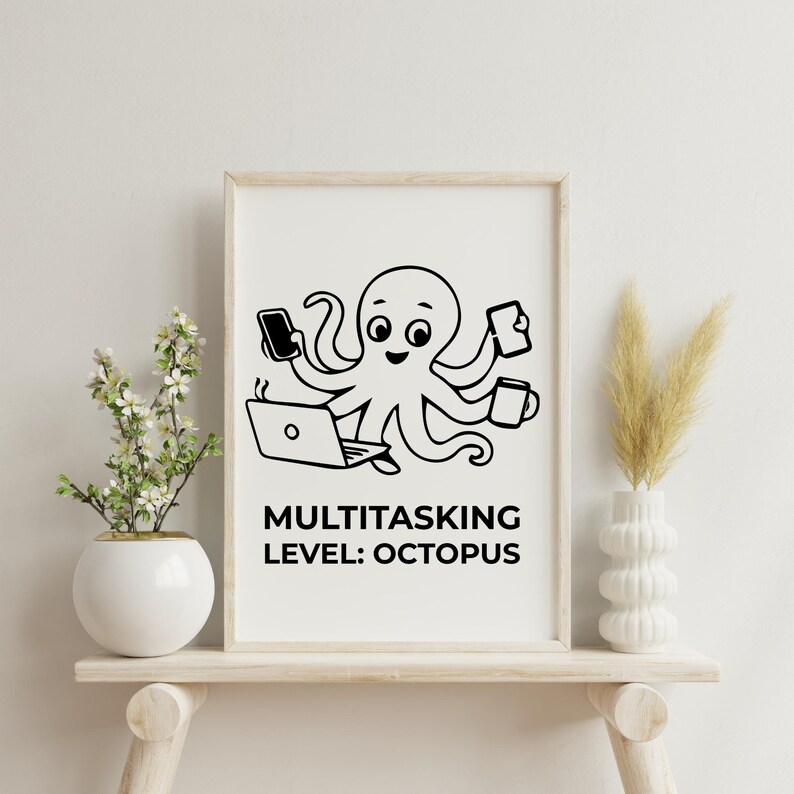 Peut inclure: Une affiche encadr&eacute;e pr&eacute;sente un dessin d'un poulpe avec plusieurs bras, chacun tenant un t&eacute;l&eacute;phone, une tasse, un ordinateur portable et une tablette. Le texte en dessous indique "MULTITASKING LEVEL: OCTOPUS" en lettres noires grasses. L'affiche est sur une &eacute;tag&egrave;re en bois clair.