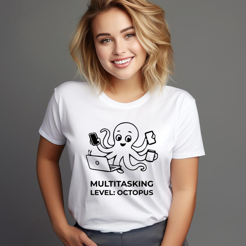 Peut inclure: T-shirt blanc avec un motif de pieuvre noir et blanc. La pieuvre est repr&eacute;sent&eacute;e en train de faire plusieurs choses &agrave; la fois avec un t&eacute;l&eacute;phone, une tasse de caf&eacute;, un ordinateur portable et un bloc-notes. Le texte "MULTITASKING LEVEL: OCTOPUS" est imprim&eacute; en dessous.