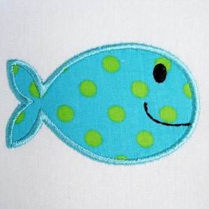 May include: A blue and green fabric fish with a smiling face and black eyes. The fish is decorated with green polka dots.