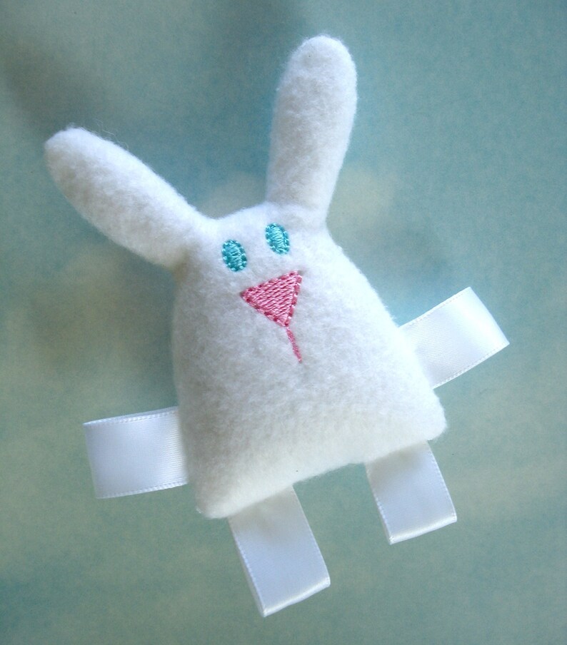 May include: White plush bunny toy with embroidered blue eyes and a pink nose. The bunny has white satin ribbon arms and legs.