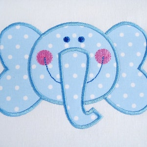 May include: A blue and white polka dot elephant applique with pink cheeks and blue eyes. The elephant is outlined in blue thread.