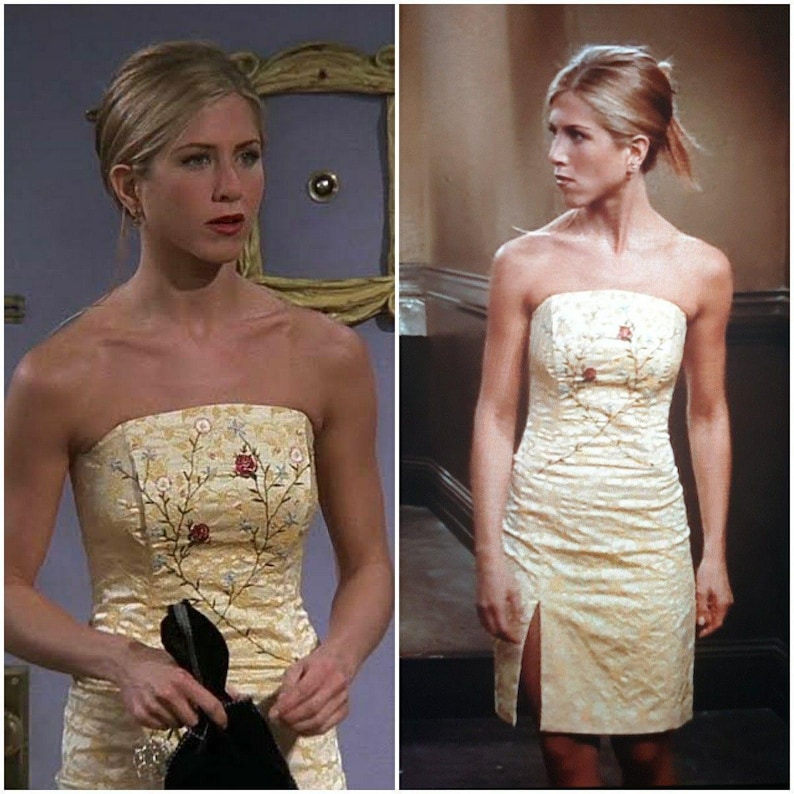 Puede incluir: Un vestido amarillo sin tirantes con un estampado floral y una abertura lateral. El vestido est&aacute; hecho de una tela sedosa y tiene un corpi&ntilde;o ajustado.