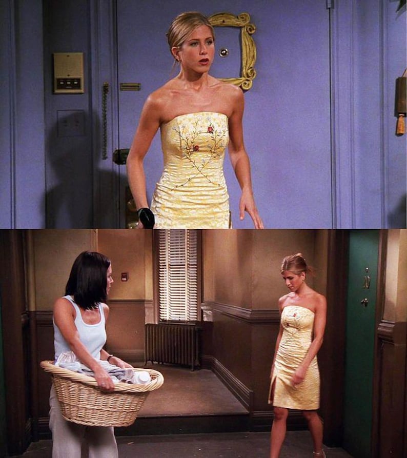 Puede incluir: Una mujer con un vestido amarillo sin tirantes con bordados florales. El vestido tiene un corpi&ntilde;o ajustado y una falda fluida. La mujer est&aacute; de pie en un pasillo con una puerta en el fondo.