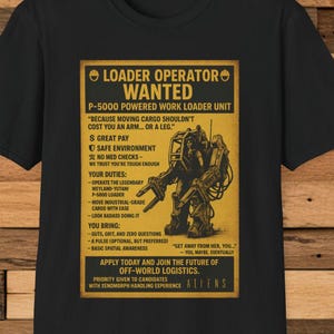 May include: Black t-shirt featuring a yellow poster design with text and a graphic of a P-5000 Powered Work Loader Unit. The poster text includes "Loader Operator Wanted" and "Aliens".