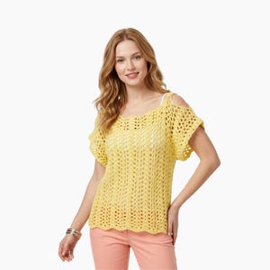 Könnte beinhalten: Ein gelbes Häkeltop mit kurzen Ärmeln und ausgeschnittenen Schultern. Das Oberteil hat einen wellenförmigen Ausschnitt und ein lockeres, offenes Webmuster. Das Model trägt ein weißes Unterhemd und eine pfirsichfarbene Hose. Am Handgelenk des Models befindet sich ein silbernes Armband.