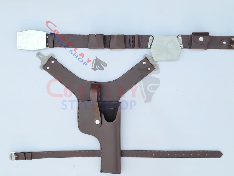 Op de afbeelding: Een bruine leren cosplay riem- en holsterset. De riem heeft zilverkleurige rechthoekige en zeshoekige gespen. De holster is ontworpen om een rekwapen te bevatten. De set bevat een schouderharnas en een tailleband.
