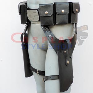 Puede incluir: Cintur&oacute;n utilitario de cuero negro con m&uacute;ltiples bolsas y fundas. El cintur&oacute;n presenta una hebilla de color plateado y est&aacute; dise&ntilde;ado para usarse alrededor de la cintura y las piernas. Las bolsas se aseguran con broches dorados.