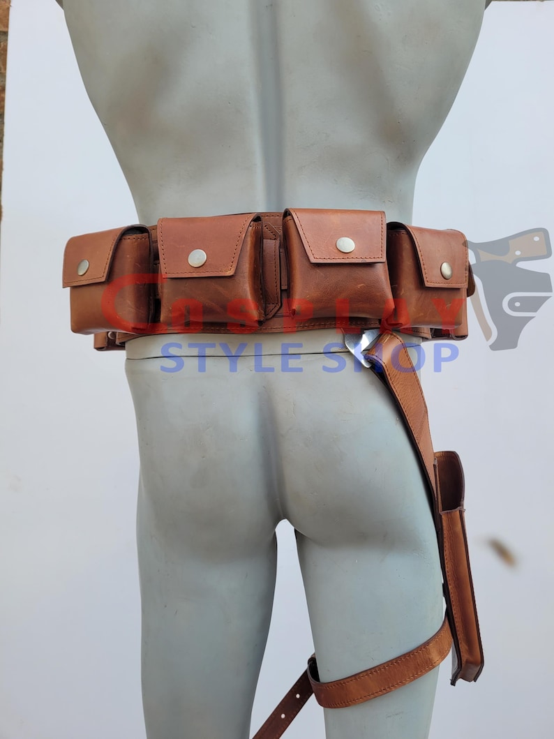 May include: A brown leather utility belt with multiple pouches and a leg strap. The belt features several square pouches with silver button closures. The leg strap has a small holster. The text "STYLE SHOP" is visible.