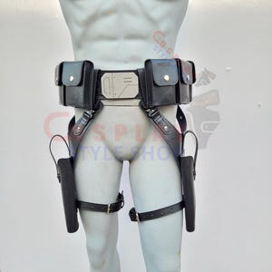 May include: Black leather utility belt with two pouches, a silver buckle, and two holster leg straps. The belt is displayed on a mannequin. The belt has a futuristic design.