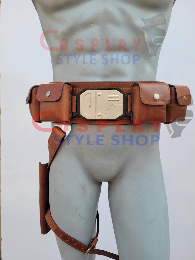 May include: A brown leather utility belt with multiple pouches and a holster. The belt features a rectangular silver buckle and is designed to be worn around the waist. The text "COSPLAY STYLE SHOP" is visible in the background.