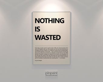 May include: A framed poster with the words "NOTHING IS WASTED" in bold black letters. Below the text is a paragraph of inspirational text. The poster is displayed on a white wall.