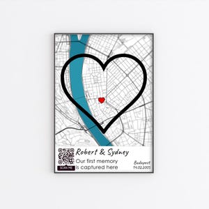 May include: A black and white map of Budapest, Hungary with a black heart drawn over it. The heart is filled with a blue river and a red dot in the center. The text "Robert & Sydney" is at the bottom of the map, along with the text "Our first memory is captured here" and the date "19.02.2005".