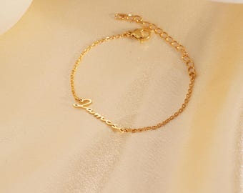 May include: Gold chain bracelet with the name "James" written in cursive.